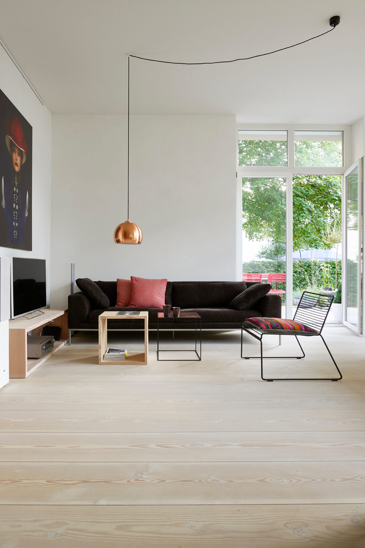 Großes offenes Wohnzimmer mit hellem Dielenboden aus Douglasienholz und dunklem Sofa