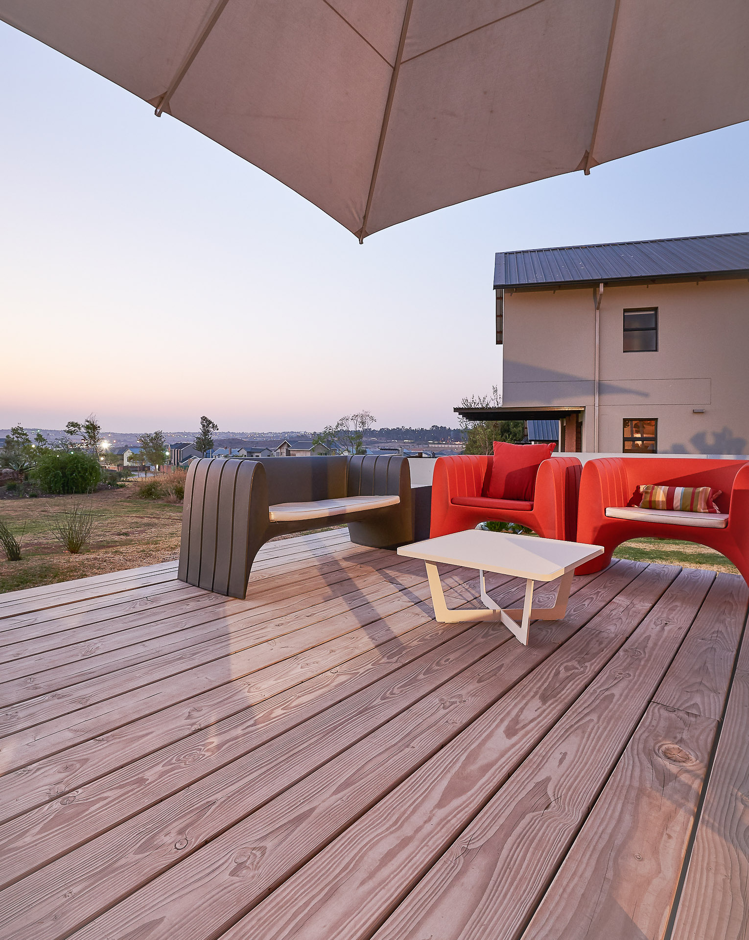 Offene Terrasse mit Holzdielen, Outdoormöbeln und Sonnenschirm