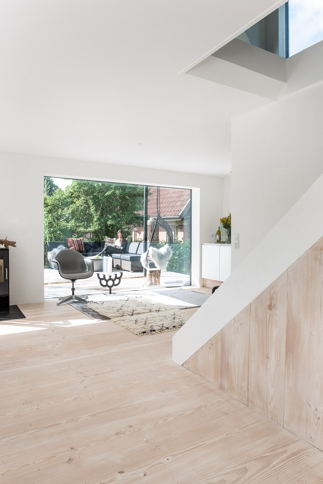 Wohnzimmer mit hellem Dielenboden und weißen Wänden mit Blick auf Außenterrasse