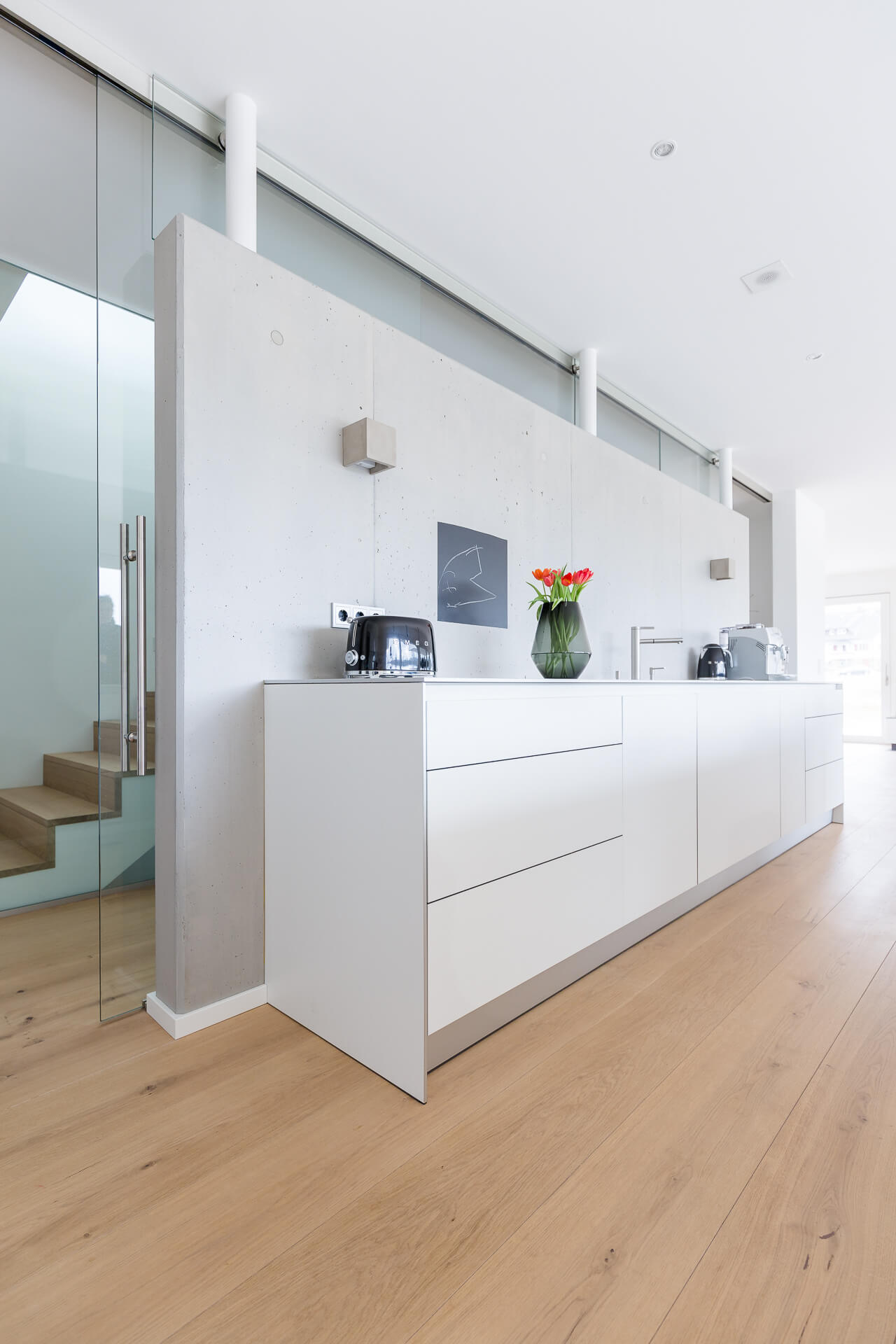 Cuisine ouverte blanche dans maison d'habitation avec parquet en chêne