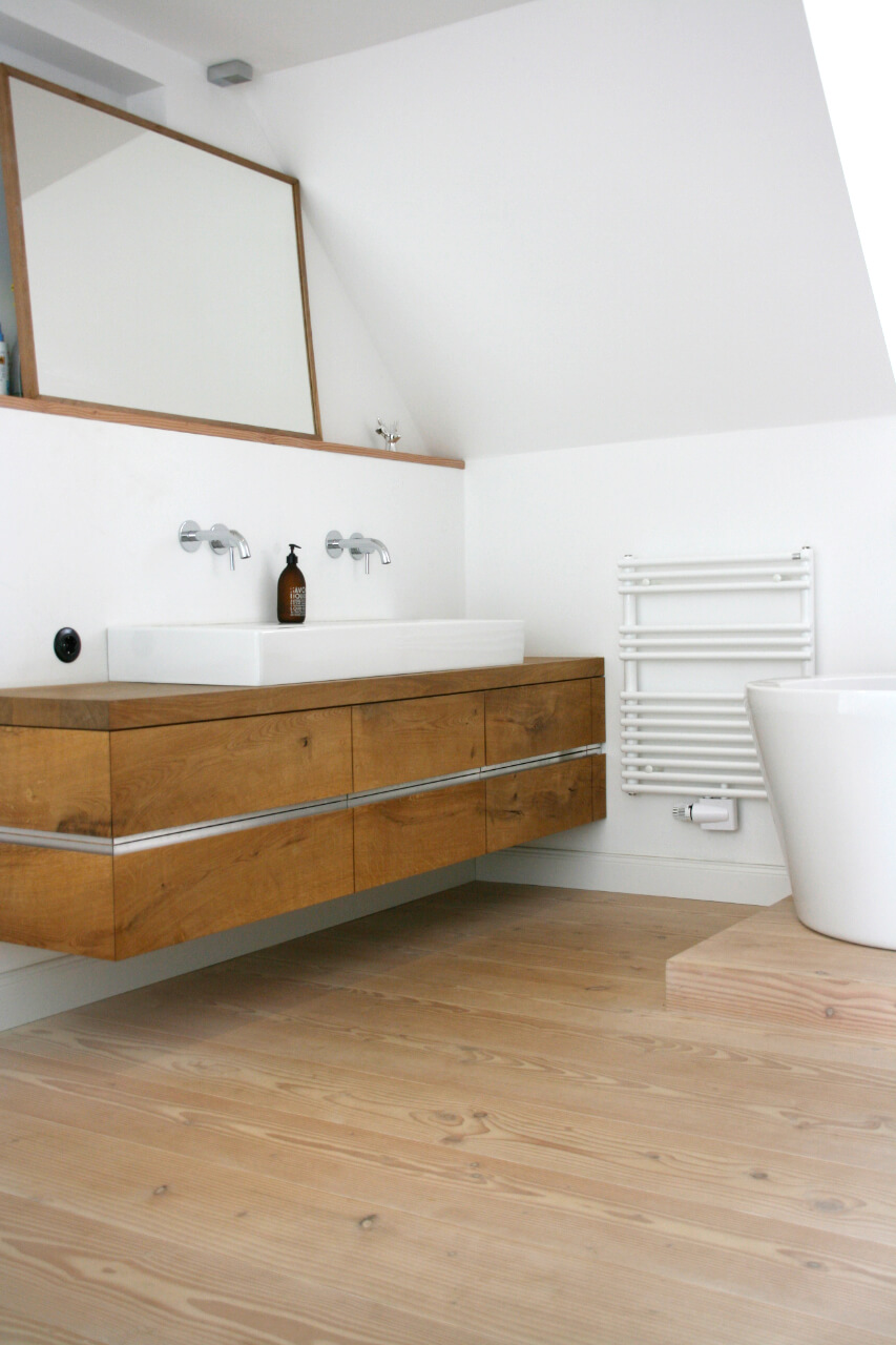 Bad mit Dielenboden aus hellem Holz sowie Waschschrank und Spiegel