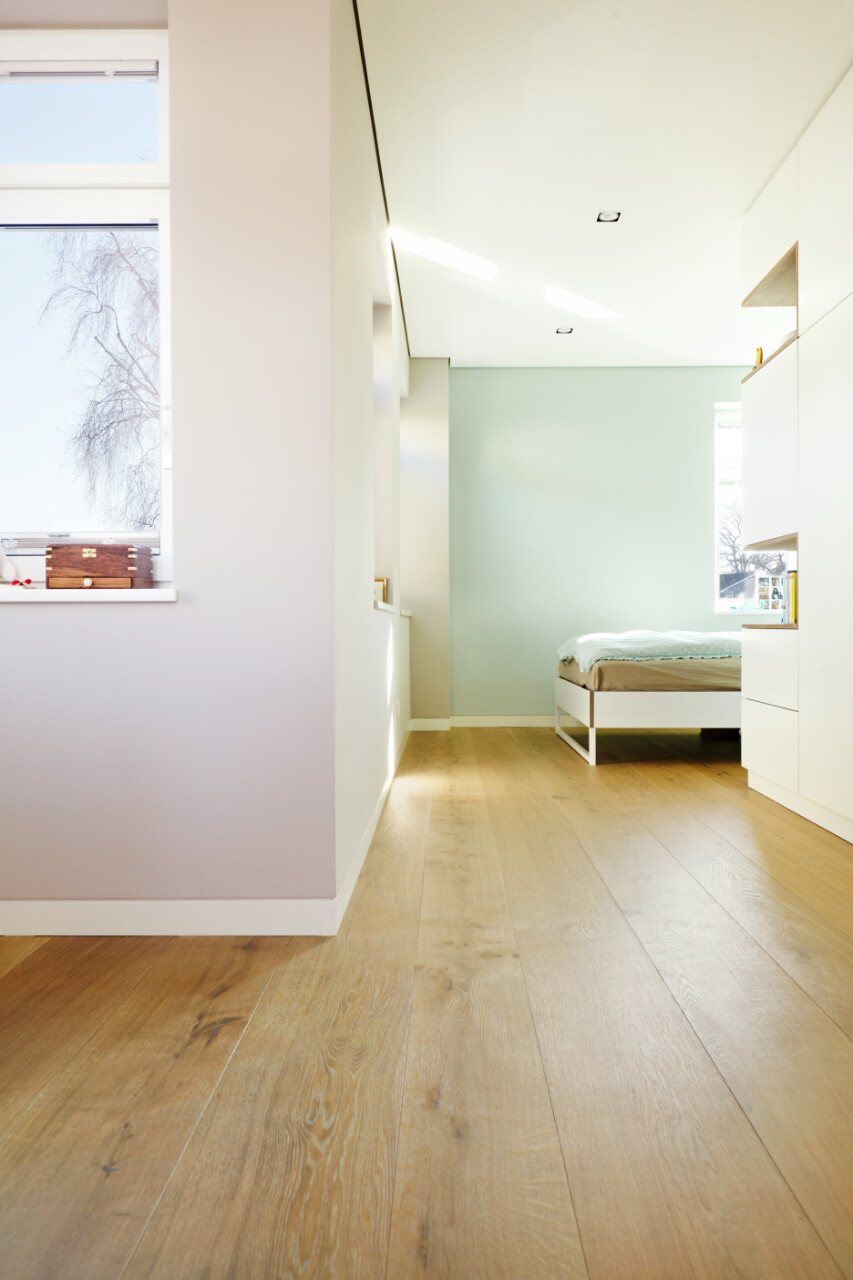 Helles Schlafzimmer mit Fenstern und warmem, raumlangem Eiche Dielenboden