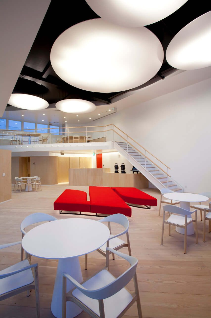 Großer heller Showroom mit hellem Dielenboden und rotem Sofa in S-Form