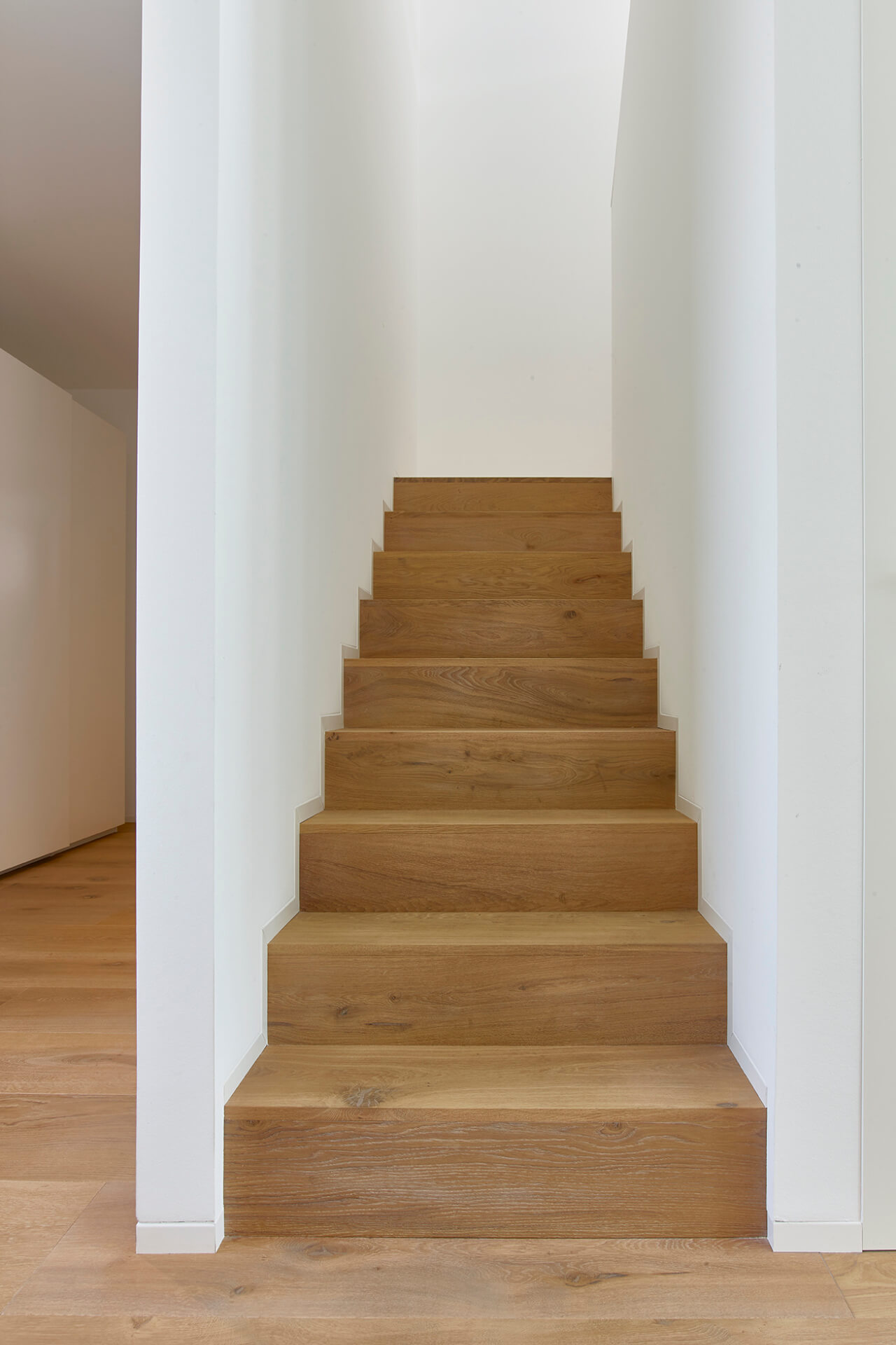 Treppe in Wohnhaus mit Stufen aus Eichenholz und passendem Dielenboden